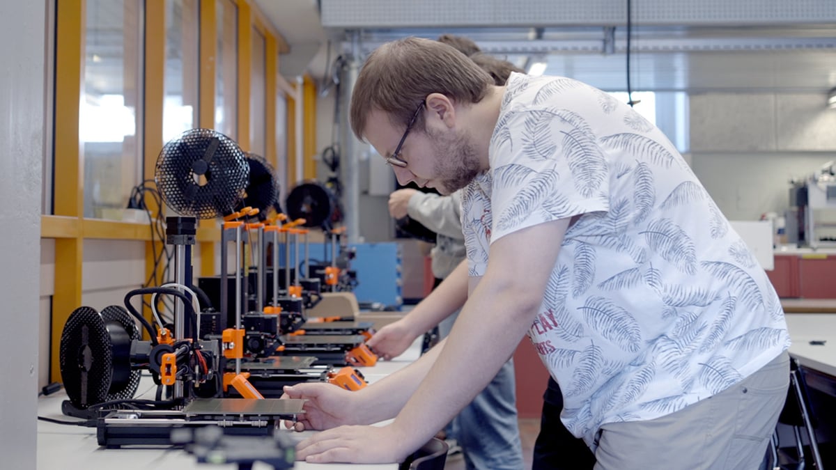 Student pracujący przy rzędzie drukarek Original Prusa w ZHAW
