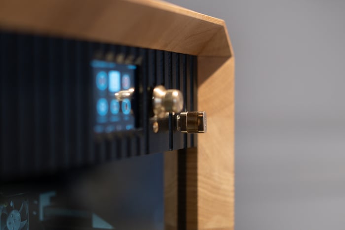 Close-up of the precision metal door hinge set into the oak and glass facade